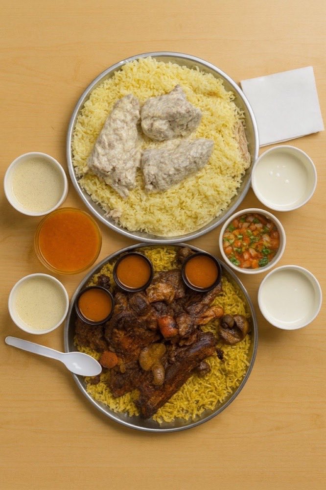 An overhead table of Old School dishes: rice, stewed lamb, yoghurt and sauces in small bowls.